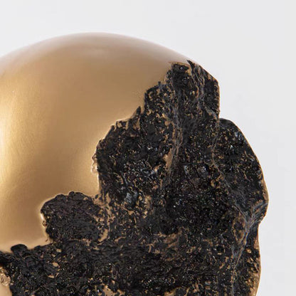 Rundt kugleornament i sort og guld på sokkel – moderne boligdekoration